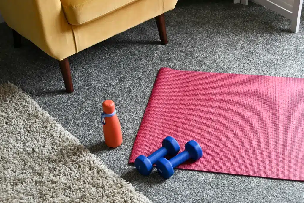 A cozy home corner set up as a workout space with a mat, water bottle, and weights