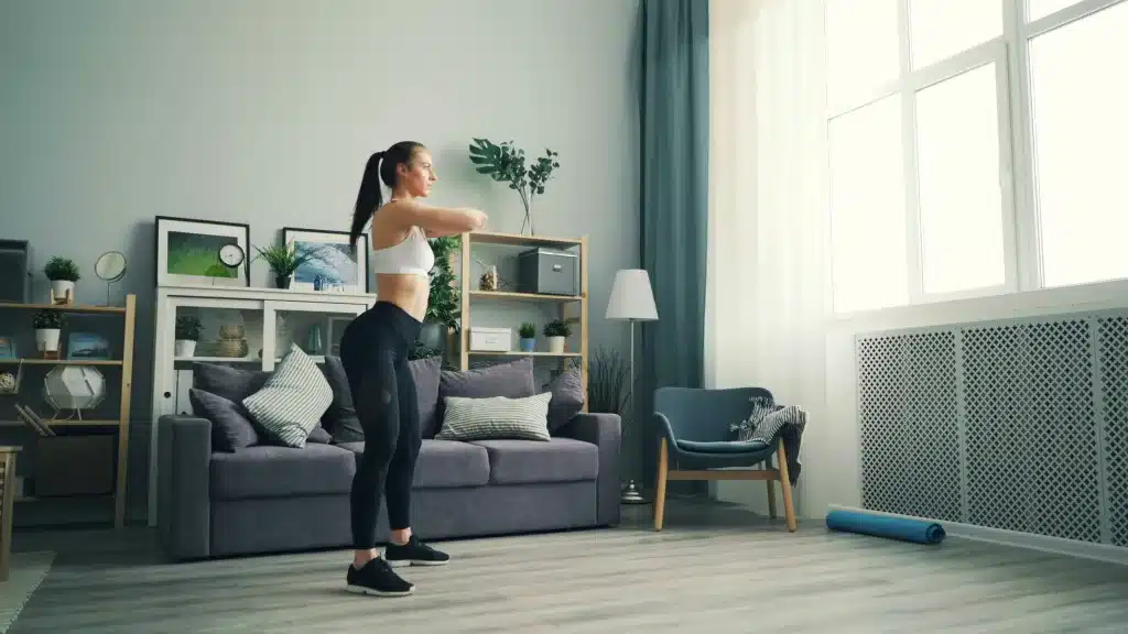 a woman in a living room doing squats demonstrating Home Workout Ideas for All Fitness Levels
